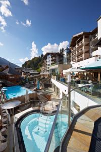 um resort com piscina com escorrega em Hotel Alpine Palace em Saalbach-Hinterglemm