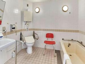 W łazience znajduje się toaleta i czerwone krzesło. w obiekcie LiVEMAX RESORT Hakodate Greenpia Onuma w mieście Mori