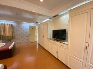 a living room with a flat screen tv and a bed at Stone House Quezon City in Manila