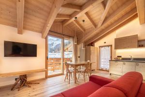 Mas del Mezdì - mountain chalet Val di Rabbi في رابي: غرفة معيشة مع أريكة حمراء وطاولة