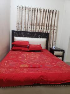 ダッカにあるLovely two bed flats by Dhaka Shahjalal Airportの赤いベッド1台(赤い枕付)が備わるベッドルーム1室を提供しています。