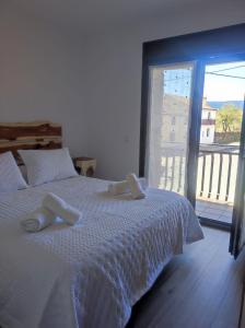 a bedroom with a white bed with a balcony at Apartamentos Sierra y Mar Aldealengua de Pedraza in Ceguilla