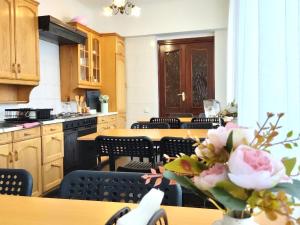 a kitchen with wooden cabinets and a table with flowers at Like Home Guest Rooms in Almaty