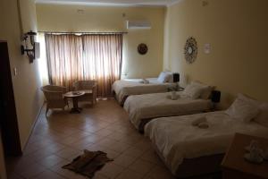 a hotel room with two beds and a table at Farmhouse Boutique Backyard Rooms in Outjo +152 photos