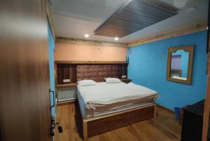 1 dormitorio con 1 cama con pared azul en Hotel Payal Mall Road Lake View Nainital - Prime Location - Spacious and Hygiene Room, en Nainital