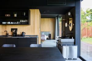 富士河口湖的住宿－GEN.（富士クラシックホテル），厨房配有黑色橱柜和带椅子的柜台。