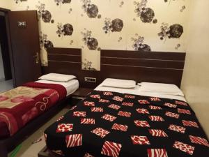 a bedroom with two beds and a wall with flowers at Hotel Royal Palace Mysuru in Mysore