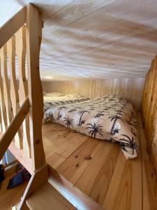 a bed in a tiny house with a wooden floor at Le Grab in Saint-Jacques-des-Blats