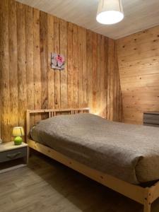a bedroom with a bed in a room with wooden walls at Le Grab in Saint-Jacques-des-Blats