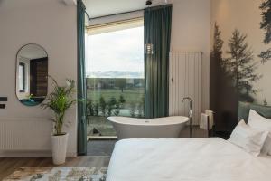 een badkamer met een bad, een bed en een raam bij Green Resort Bran in Bran