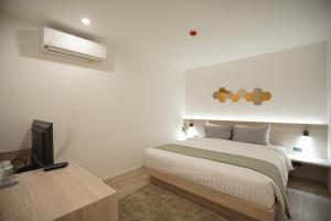 1 dormitorio con 1 cama y escritorio con TV en E11 Hotel, en Amphoe Phra Khanong