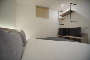 1 dormitorio con 1 cama blanca y TV de pantalla plana en E11 Hotel, en Amphoe Phra Khanong