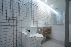 Baño de azulejos blancos con aseo y lavamanos en E11 Hotel, en Amphoe Phra Khanong