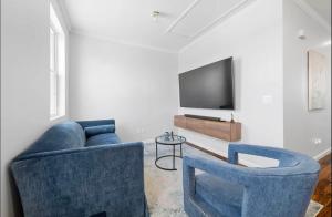 a living room with two blue chairs and a television at Stylish Apt in Jersey City 20 min to NYC in Union City