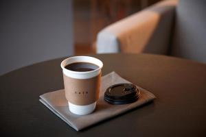 Shilla Stay Plus Ihotewoo في جيجو: كوب من القهوة على طاولة مع ساعة