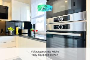 eine Küche mit einem Edelstahlofen und weißen Schränken in der Unterkunft Auszeit Apartment SUNNY in Friedrichshafen + 13 Fotos