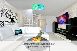 ein Wohnzimmer mit einem weißen Sofa und einem Fernseher in der Unterkunft Auszeit Apartment SUNNY in Friedrichshafen
