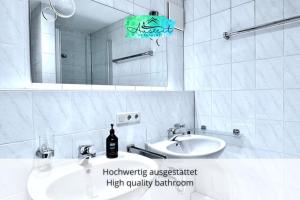ein weißes Badezimmer mit Waschbecken und Spiegel in der Unterkunft Auszeit Apartment SUNNY in Friedrichshafen