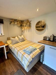 a small bedroom with a bed with a plaid blanket at Apple tree hut, in a private garden in Skipton