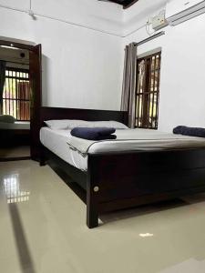 two beds in a room with two windows at Puthukkeril Heritage Home in Talavadi