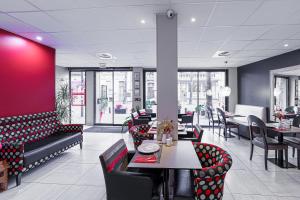un ristorante con tavoli, sedie e una parete rossa di Nyx Hôtel Indépendant a Perpignano
