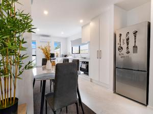a kitchen with a table with a chair and a refrigerator at Entire Brand New Home in Christchurch