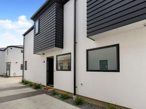 a white house with a black roof and windows at Entire Brand New Home in Christchurch