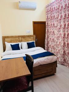 1 dormitorio con cama, mesa y cortinas en Bobby’s B&B, en Lucknow