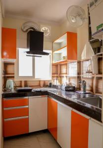 eine Küche mit orangefarbenen und weißen Schränken und einem Waschbecken in der Unterkunft Bobby’s B&B in Lucknow
