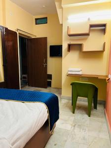 een hotelkamer met een bed en een groene stoel bij Bobby’s B&B in Lucknow