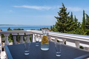 a table with glasses and a bottle on a balcony at Apartments Prkačin 2 in Starigrad
