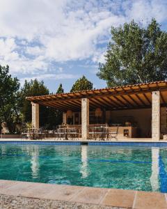 ein Pool mit einem Pavillon mit Tischen und Stühlen in der Unterkunft Petrino Eco Village in Afytos