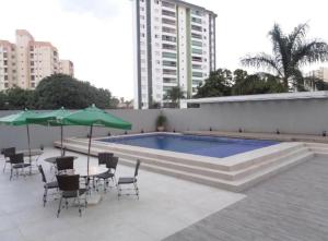 een zwembad met stoelen, tafels en parasols bij Hotel Crystal Place in Goiânia