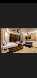 una camera con un grande letto e una TV a schermo piatto di Hotel Green Park a Mumbai