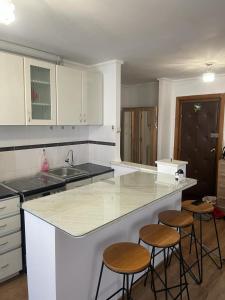 a kitchen with a counter and three bar stools at Mara Central in Baia Mare