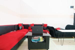 a living room with a red couch with a laptop on a table at OYO 93834 The Jarrdin Apartment By Yedi Property in Bandung