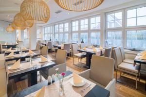 ein Restaurant mit Tischen, Stühlen und Fenstern in der Unterkunft Logierhus Langeoog in Langeoog