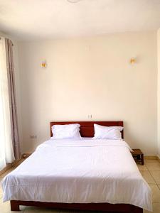 a bedroom with a large bed with white sheets at BELINDA APPARTEMENT in Rubavu
