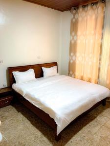 BELINDA APPARTEMENT في Rubavu: غرفة نوم بسرير كبير مع شراشف بيضاء