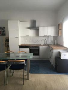 cocina con armarios blancos, mesa y sillas en Apartment Julia en Supetarska Draga