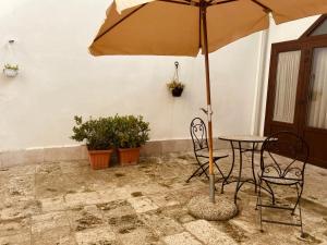 una mesa y sillas con una sombrilla en el patio en La Stalla, en Gravina in Puglia