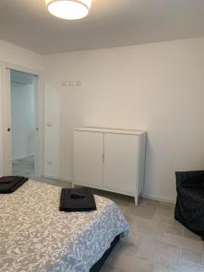 biała sypialnia z łóżkiem i komodą w obiekcie Piccola Corte w mieście Udine