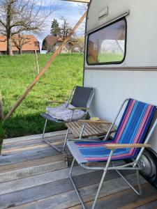 zwei Stühle auf einem Deck neben einem Wohnmobil in der Unterkunft Tiny Paradise in Bern