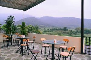 a patio with tables and chairs and a view of mountains at Phúc Hưng Kazin Homestay Ba vì in Ba Vì +14 photos
