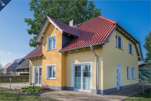 una casa amarilla con techo rojo en Ferienwohnung Sonneneck, en Kachlin