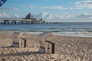 twee stoelen op het strand met een pier op de achtergrond bij Villa Seeland Villa Seeland App 3 in Heringsdorf