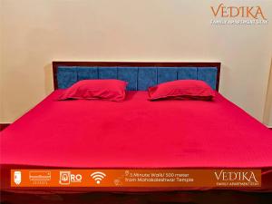 Una cama roja con dos almohadas rojas. en Vedika Yatri Grah - Entire Apartment en Ujjain