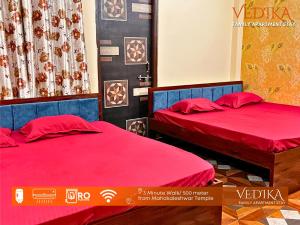 - 2 lits dans une chambre avec des draps rouges dans l'établissement Vedika Yatri Grah - Entire Apartment, à Ujjain