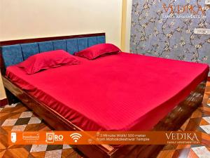 Elle comprend un grand lit avec des draps rouges et des oreillers rouges. dans l'établissement Vedika Yatri Grah - Entire Apartment, à Ujjain
