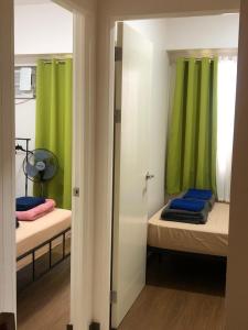 een kamer met 2 bedden en groene gordijnen bij M&M Residence in Manilla